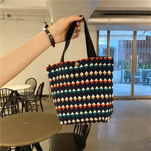 Dettaglio della borsa a pieghe geometrica colorata con bottone e manico nero