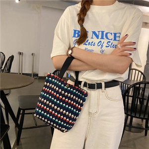 Dettaglio di una borsa in tessuto blu con motivi geometrici colorati e manici neri