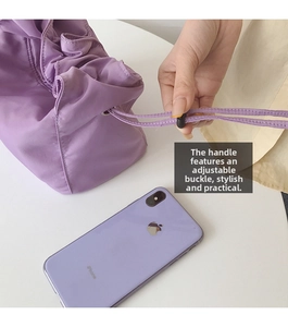Détail de la boucle réglable sur un sac baguette en nylon lilas avec smartphone