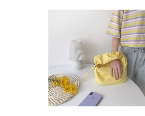 Détail du sac baguette en nylon jaune avec poignée froncée et cordon de serrage latéral