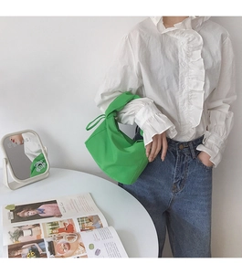 Détail du sac baguette vert vif minimaliste avec une poignée nouée élégante et moderne