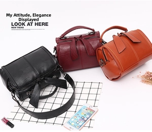 Draufsicht auf drei strukturierte Leder-Boston-Taschen in Schwarz, Burgund und Orange