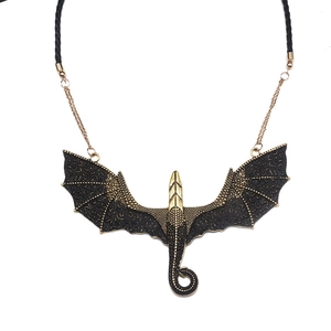 Detailed view of the antique gold dragon pendant with black leather cord and wings