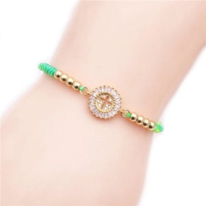 Green braided adjustable bracelet with golden beads and a micro-set zircon cross charm