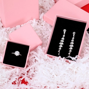 Overhead view of various pink jewelry boxes with black lining on white paper filler