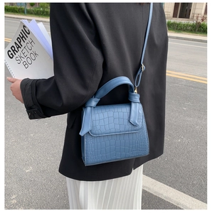 Detailed close-up of blue crocodile texture faux leather bag with handle and metal clasp