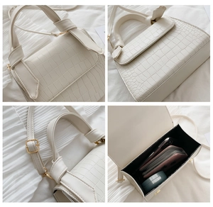 Detail view of white crocodile pattern bag showing metal buckle and interior capacity