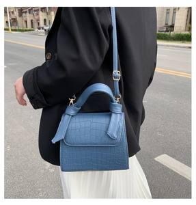 Blue crocodile pattern mini bag worn by a model in black blazer and white skirt