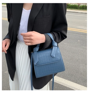 Detail shot of blue crocodile pattern leather texture and knot handle on crossbody bag