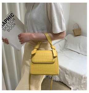 Detail of yellow crocodile embossed leather crossbody bag with decorative knotted handle