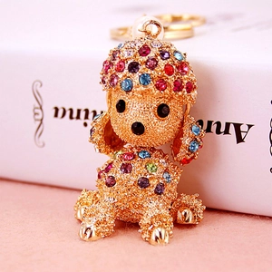 Golden poodle keychain featuring colorful rhinestones and a white pearl on a pink background