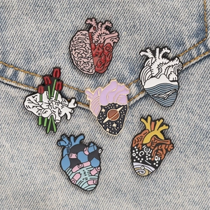 Detail of six creative anatomical heart enamel pins on a blue denim jacket pocket
