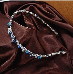 Elegant narrow silver headband with blue and clear crystal rhinestones on silk background