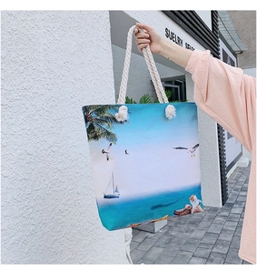 Detail of canvas tote bag featuring beach print and thick white cotton rope handles