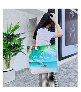 Detail of beach tote bag with island print and sturdy white rope handle worn by model