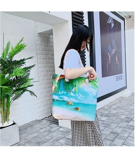 Outdoor shot showing the large capacity canvas tote bag with tropical beach print and rope handles