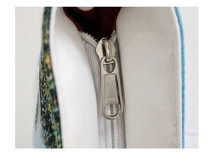 Detail of high-quality silver YKK zipper on a woven linen tote bag with burgundy lining