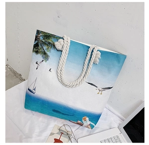 Detail of beach tote bag featuring coastal scenery print and white rope handles