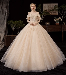 Detail of champagne gold off-shoulder bridal gown with intricate beadwork and sequins