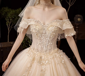 Detail of off-shoulder champagne wedding dress with sequins and 3D flower lace