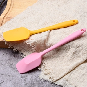 Yellow and pink food grade silicone spatulas for baking on a rustic kitchen tabletop