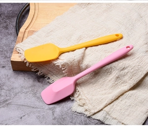 Detail of small pink and yellow food-grade silicone spatulas on linen cloth surface