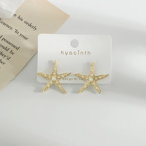 Elegant gold starfish stud earrings with white faux pearls on display card