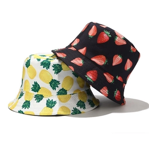 Detail view of cotton bucket hats featuring pineapple and strawberry fruit print patterns