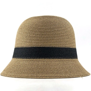 Minimalist straw bucket hat in light brown with a wide black ribbon and weave texture