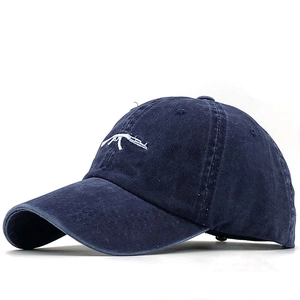 Close-up of white AK-47 rifle embroidery on washed navy blue cotton baseball cap