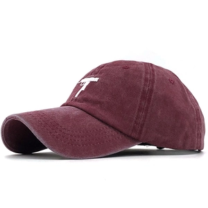 Macro detail of the white gun embroidery on a vintage burgundy washed cotton baseball cap