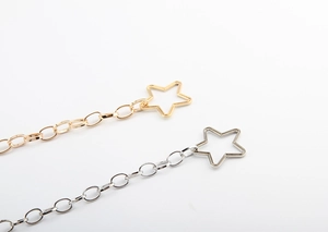 Detail of star pendant waist chain belts in metallic gold and silver finish for dresses