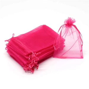 Detail of pink organza gift bags featuring golden coral patterns and drawstring closure