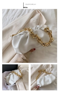 Detail of white pleated cloud bag with chunky gold chain strap on soft neutral suit