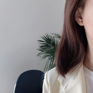 Detail showing an irregular golden silver stud earring on ear with a minimalist vibe