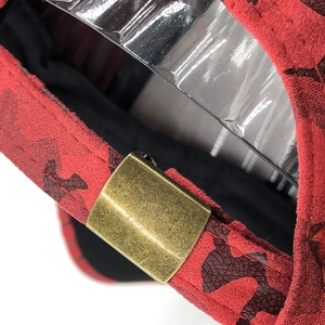 Detail of adjustable vintage brass buckle on red camouflage suede baseball cap