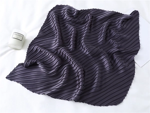 Detailed close-up of dark purple pleated satin scarf with elegant wavy texture