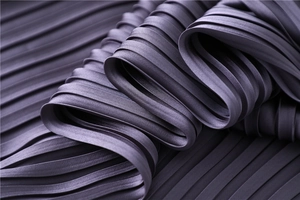 Detailed close-up of dark purple pleated satin fabric with a silky glossy texture