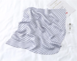 Detail shot of silver-grey pleated silk-like scarf with fine texture on white fabric