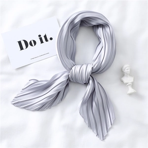 Detail of lavender pleated silk scarf with satin texture laid on a white fabric background