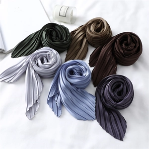 Detail of multi-color pleated satin scarves with fine accordion folds on white fabric