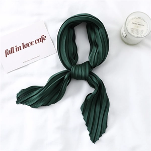 Close-up of deep green pleated satin scarf texture with elegant accordion folds