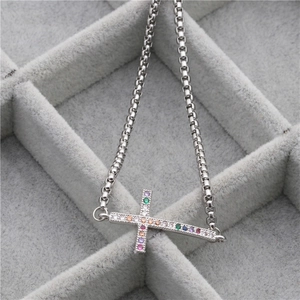 Silbernes Edelstahl-Armband mit Regenbogen-Zirkonia-Kreuz auf grauem Schmucktablett