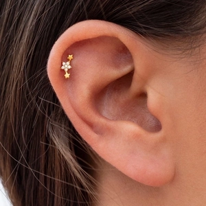 Elegant gold triple star earrings with zircon inlay shown on model's ear profile