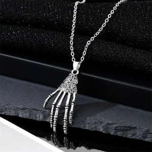 Gothic punk skeleton hand pendant necklace with silver finish on black stone background