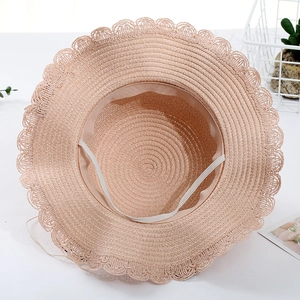Detail view of pink straw hat interior showing woven texture and elastic windproof strap