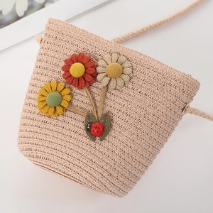 Detailed macro of kids woven straw crossbody bag with floral appliques and ladybug