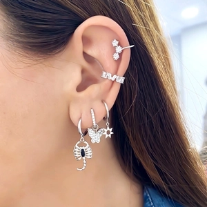 Silver constellation earring set with zircon sun and scorpion charms worn on ear