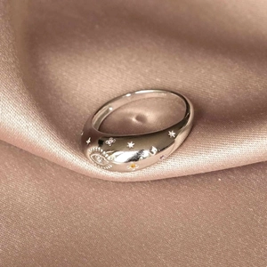 Polished silver moon and star ring with cubic zirconia on beige satin fabric background