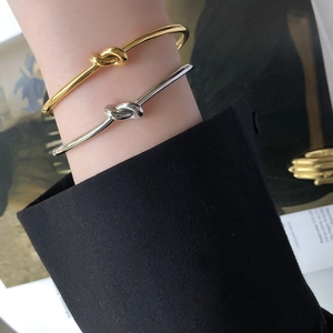 Polished gold and silver knot bangles worn together for a minimalist stylish stacked look